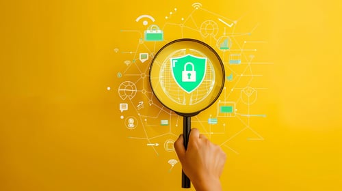 A hand holds a magnifying glass over a digital shield with a padlock, surrounded by icons representing devices, networks, and data. Symbolises monitoring, security, and compliance in managed file transfer systems.