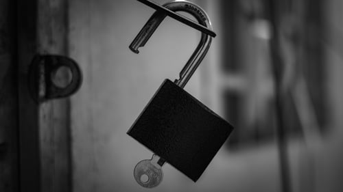 Black and white image of an opened padlock with the key inside